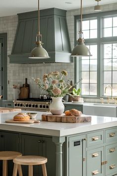 a kitchen with green cabinets and white counter tops, two stools in front of the island