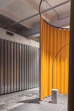 an empty room with yellow curtains and a white square object in the foreground, surrounded by metal partitions