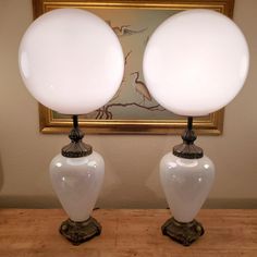 two white lamps sitting on top of a wooden table