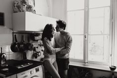 a man and woman standing next to each other in front of a washing machine, looking at each other