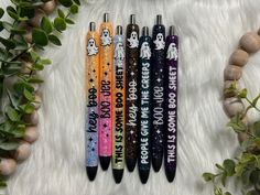 four pens with different designs on them sitting next to some plants