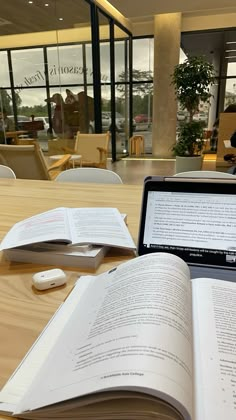 an open book sitting on top of a wooden table next to a laptop computer and mouse