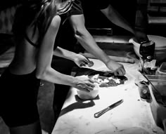 two people are preparing food on a counter in the kitchen, one woman is cutting vegetables