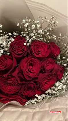 a bouquet of red roses and baby's breath in a heart - shaped box