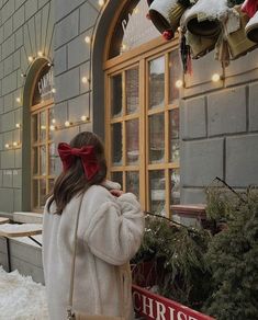 a woman standing in front of a building with christmas lights on the windows and decorations