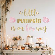 a little pumpkin is on her way sign next to a table with cakes and candles