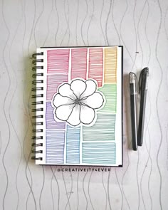 a notepad with a flower drawn on it next to a pen and paper clip