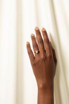 a woman's hand with a gold ring on top of her left hand, against a white background