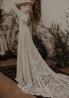 a woman in a wedding dress standing on a rug with her arms behind her back