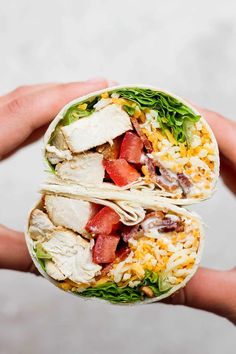 two burritos filled with chicken, lettuce and tomatoes on top of rice