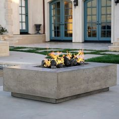 a fire pit sitting on top of a cement slab in front of a building with blue doors