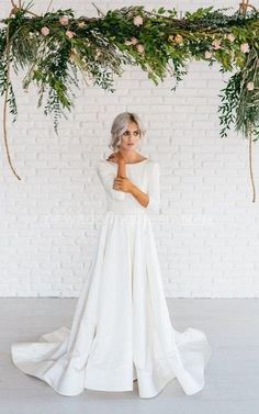 a woman in a white dress standing under a floral arch