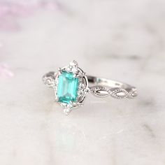 Gorgeous Vintage Inspired Paraiba Tourmaline Ring ►Made of solid sterling silver with rhodium finish (925) ►Accented With Simulated Diamonds (CZ) ►Average band width: 2 mm Center Stone: Paraiba Tourmaline Color: Turquoise Shape: Emerald Gem size: 6.0 x 4.0 mm Carat Weight: 1 ct. (approx.) Gemstone creation: lab-grown Hardness: 7-7.5 (Mohs scale) ✓ 100% Nickel-Free ✓ Hypoallergenic ✓ Comfort Fit ✓ Free Ring Box ✓ Free USA Shipping Turquoise Emerald Cut Jewelry For Anniversary, Emerald Cut Turquoise Jewelry For Wedding, Vintage Emerald Ring For Promise, Turquoise Emerald-cut Jewelry For Wedding, Turquoise Gemstone Rings With Emerald Cut, Turquoise Emerald-cut Gemstone Ring, Turquoise Emerald Cut Gemstone Ring, Turquoise Emerald Ring For Anniversary, Emerald Cut Turquoise Gemstone Ring