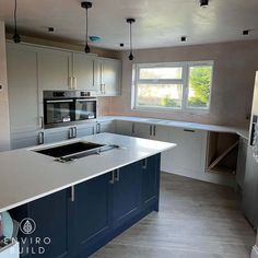 an empty kitchen with blue cabinets and white counter tops is seen in this image from the front view