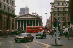 cars, buses and pedestrians on a busy street in the british city with tall buildings