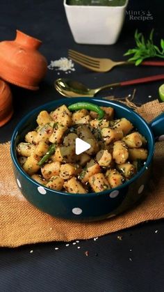 a blue bowl filled with food on top of a table next to utensils