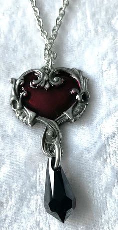 A dark and Delphic romance of the heart; an assignation between two strange and exotic creatures from another place, amorous beneath the stars in the night sky. A delicate but striking pendant perfect for everyday wear. A delicate pewter heart pendant, the centre piece enamelled in a transparent red and surrounded by an antiqued pewter Baroque frame with a skull profile on either side. There is a black crystal teardrop suspended below and the pendant hangs from a pewter bale. The pendant comes w Skull Profile, Beneath The Stars, Baroque Frame, Baroque Frames, Edgy Jewelry, Jewelry Accessories Ideas, Rose Rouge, Chunky Jewelry