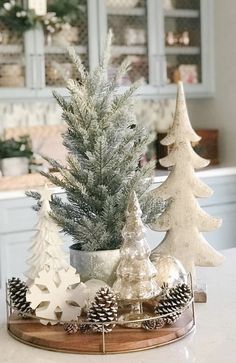 small christmas trees are sitting on a tray in front of a kitchen counter with white cabinets