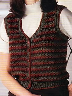 a woman wearing a crocheted vest with buttons on the front and back, standing in front of a white wall