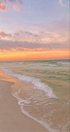 an ocean beach with waves coming in to shore and the sun setting on the horizon