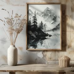 a white vase sitting on top of a wooden table next to a wall mounted painting