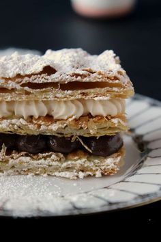 a plate that has some kind of dessert on it with powdered sugar and chocolate