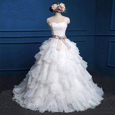 a white wedding dress on display in front of a blue wall with flowers and ribbons