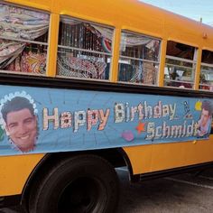 a yellow school bus with a happy birthday banner on the side and an image of a man's face