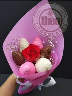 a person is holding a bouquet of chocolates and roses in pink paper wrapper