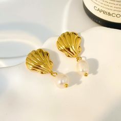 Experience the beauty of the ocean with our stunning 18K Seashell Freshwater Pearl Earrings. These earrings feature delicate seashell pendants and lustrous freshwater pearls, creating a fashionable yet timeless look. Crafted with high-quality stainless steel, these earrings are perfect for any beach lover or fashion enthusiast. Elevate your style with our 18K Seashell Freshwater Pearl Earrings today! Elegant Shell With Pearl Charm, Shell-shaped Pearl Earrings With Pearl Charm, Pearl Shell Earrings With Pearl Charm, Elegant Gold Shell With Pearl Charm, Elegant Shell Dangle Earrings, Shell-shaped Pearl Drop Earrings For Gifts, Shell-shaped Pearl Earrings For Gift, Pearl Shell Drop Earrings With Pearl Drop Detail, Elegant Shell Drop Earrings