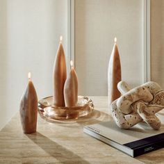 some candles are sitting on a table next to a book and an object that looks like a glove