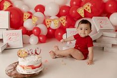 a baby sitting on the floor next to a cake and some pizza boxes in front of it