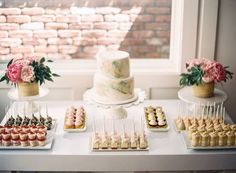 a table topped with cakes and cupcakes next to a window