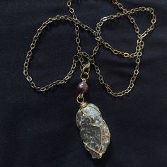 Pyrite stone from Perú, wrapped in gold plated wire, hangs from an 22-inch patinated brass chain that clasps in front. A purple lepidolite bead complements the golden color. This piece is great for honoring the Sun! It can also be used as a meditation/divination pendulum thanks to the weight and swing of the stone and front clasping. Wire Wrapped Long Necklace In Spiritual Style, Spiritual Gold Crystal Necklaces, Gold Amethyst Necklace For Healing, Healing Brass Jewelry With Natural Stones, Handmade Gold Crystal Metal Necklace, Gold Amethyst Necklace With Raw Stone, Hand Wrapped Gold Necklace With Copper Wire, Gold Necklace With Copper Wire As Gift, Gold Hand Wrapped Necklaces For Meditation