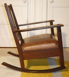 a brown leather rocking chair sitting on top of a yellow and blue rug in front of a white door