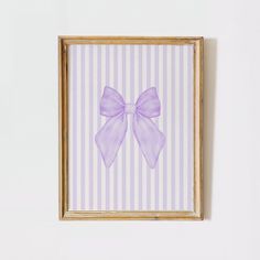 a painting with a purple bow hanging on a white wall next to a wooden frame