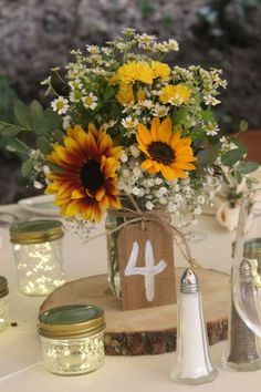 sunflowers and baby's breath flowers in mason jars on a table with candles