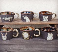 coffee cups with animals painted on them sitting on a shelf