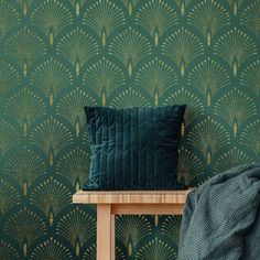 a green pillow sitting on top of a wooden table next to a wallpaper covered in leaves