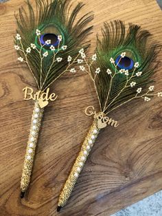 two peacock feathers with the word bride written on them and some baby's breath flowers