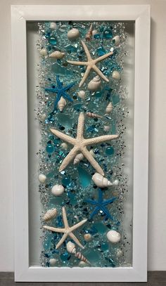 a white frame with blue sea glass and starfishs