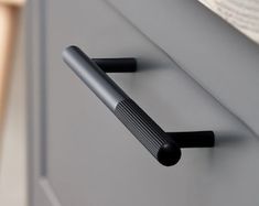 a close up of a black handle on a gray cabinet with a book in the background