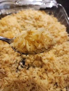 a spoon full of rice is being lifted from a casserole dish in a pan