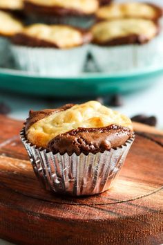 a chocolate cupcake sitting on top of a wooden cutting board next to other pastries