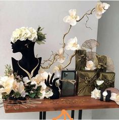 a table topped with white flowers next to a black mannequin and other items