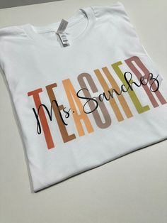 Show your appreciation for your favorite teacher with our Personalized Teacher Shirt! This custom tee makes the perfect gift for new teachers or as a thank you to your mentor. Celebrate their dedication with this unique and thoughtful Teacher Appreciation Gift. How to order 1-pick size and shirt color 2- Add to cart 3- go to cart and in the instructional box enter the custom name Example: Mrs Hernandez 4-Checkout T-shirt .unisex .eco friendly . regular size . soft & comfy Teacher Shirt With Name, Personalised T-shirt, Custom Teacher Shirts, Vinyl Teacher Shirts, Name Shirt Ideas, Dtf Shirt Ideas, Teacher T Shirt Outfits, Teacher Cricut Shirts, Tshirt Ideas For Teachers