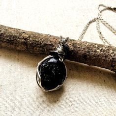 Experience bold protection and grounding when you wear this raw obsidian pendant. The men's stone necklace has a versatile design that you can easily wear it with any outfit. You customize this piece by choosing the material for its 24" chain or cord. The stone is a raw apache tear obsidian in hypoallergenic setting You choose your 24-inch chain from 18k white gold plated brass, black gunmetal, black flat leather, or black round cotton Pendant height is 2.0 Inches, width is 1.0 Inches Option to Black Crystal Pendant Necklaces For Meditation, Black Pendant Crystal Necklaces For Meditation, Spiritual Black Necklace With Raw Stone, Black Pendant Crystal Necklace For Meditation, Black Amulet Necklace With Natural Stones, Black Obsidian Necklace For Healing, Minimalist Black Pendant Crystal Necklace, Black Necklaces With Round Pendant And Natural Stones, Minimalist Black Wire Wrapped Necklace