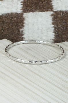 This sterling silver bangle bracelet was made by Navajo silversmith Elaine Tahe.Circumference: 8"Width: 1/8"Free shipping on all orders! We ship with USPS and always include tracking. All orders ship within a day of payment.Returns are accepted up to 30 days after you receive your order. Just send us a message. Our shop offers cash back or store credit. The item must be returned in new condition. Stackable Sterling Silver White Gold Bangle, Stackable White Gold Sterling Silver Bangle, Stackable Sterling Silver Bangle In White Gold, Minimalist Sterling Silver Stackable Bracelet, Sterling Silver Stackable Round Bangle, Stackable Sterling Silver Bangle, Sterling Silver Stackable Bangle, Silver Hammered Bangle Jewelry, Stackable Sterling Silver Bangle Bracelets