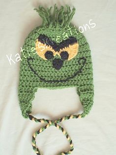 a crocheted green hat with an angry grin face