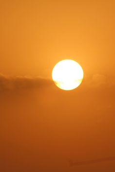 the sun is setting behind an airplane in the sky